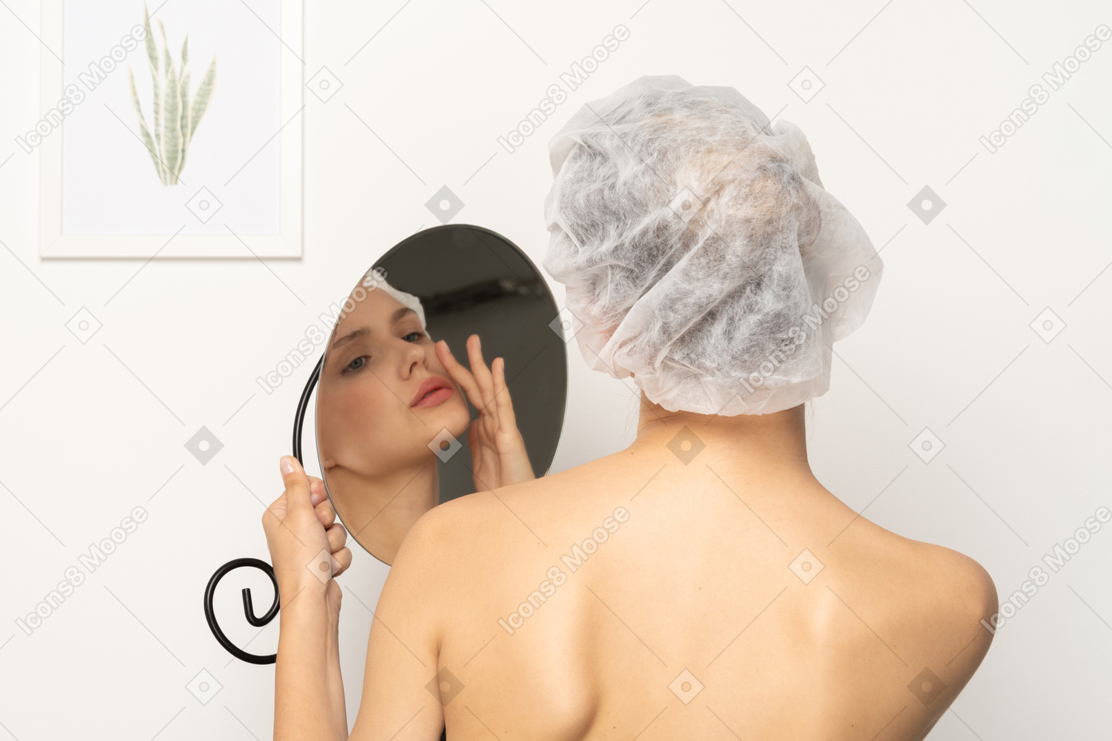 거울에 비친 자신의 모습을 바라보는 수술 모자를 쓴 여성