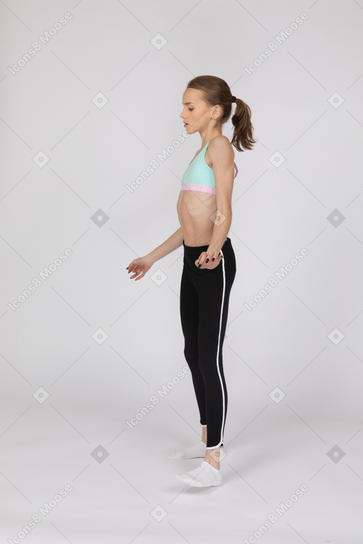 Side view of a teen girl in sportswear gesticulating and looking down