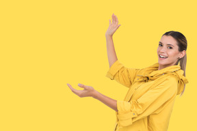 Woman in yellow raincoat showing something
