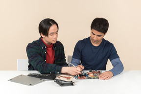 Due giovani geek con alcuni dettagli sul tavolo con alcuni problemi