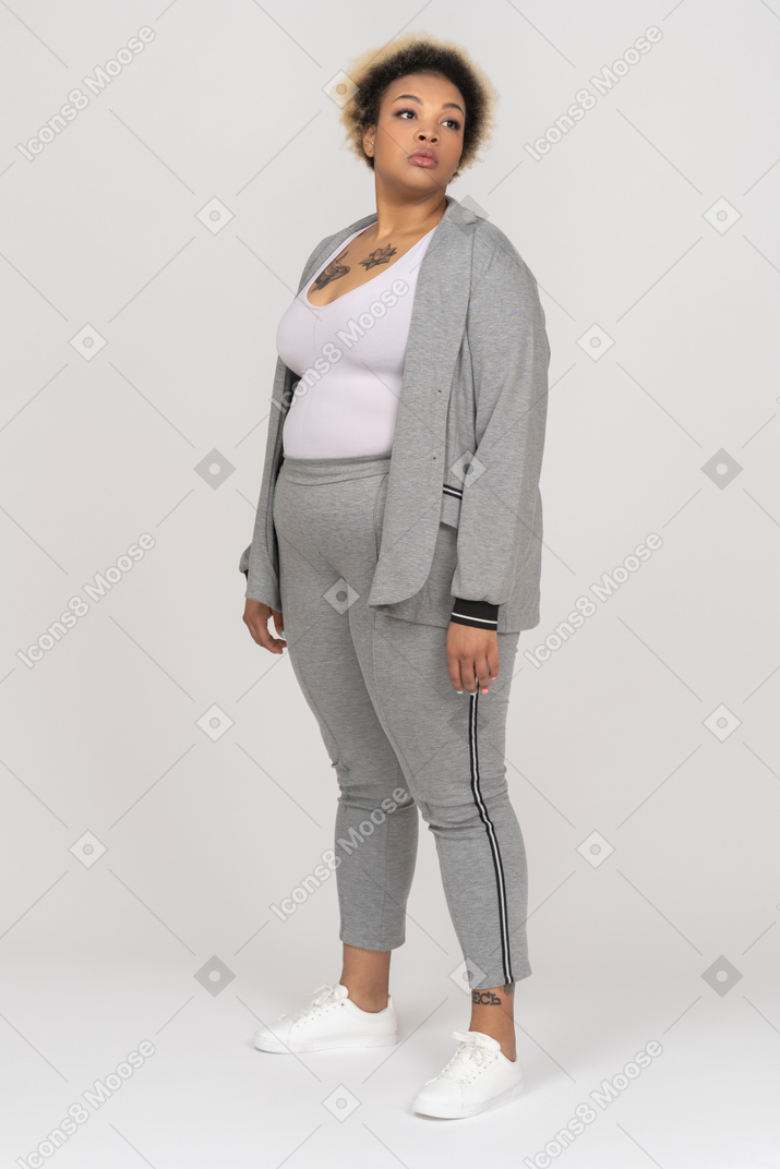 Mujer negra despreocupada en traje deportivo mirando a un lado