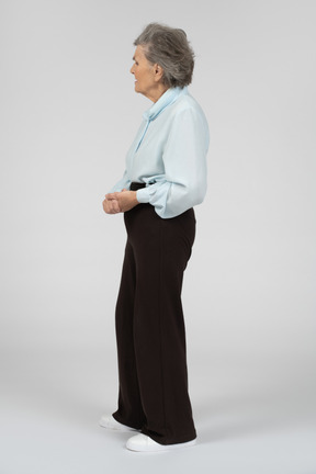 Vista laterale di una donna anziana in piedi con le mani giunte