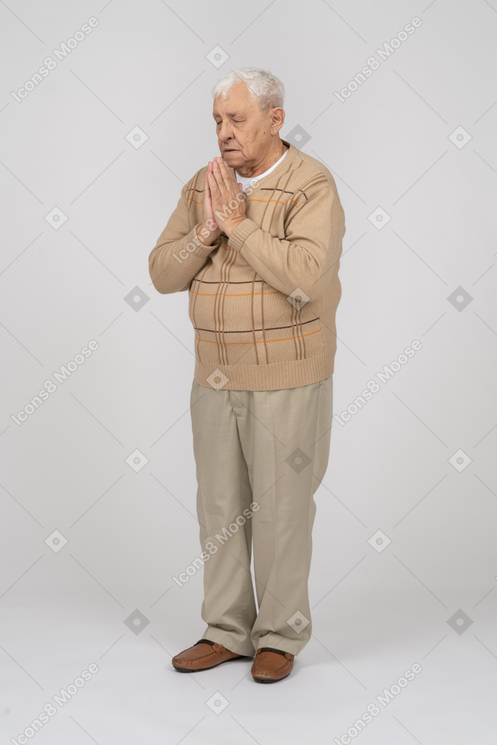 캐주얼 옷을 입은 노인의 앞모습은 기도하는 몸짓으로 손을 잡고 있다