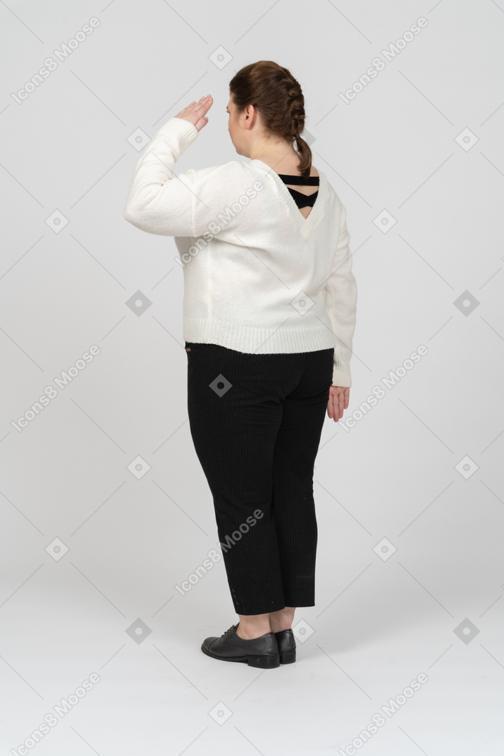 Rear view of a plus size woman in casual clothes saluting with hand