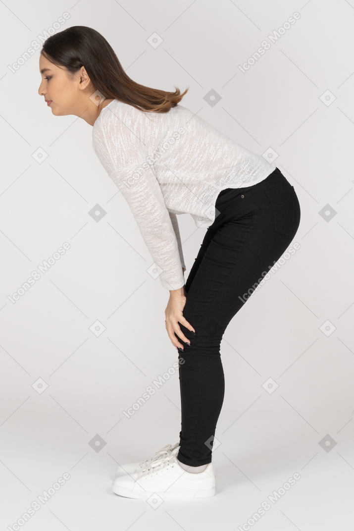 Vista lateral de una joven mujer india en ropa casual apoyado en los brazos y doblando las rodillas
