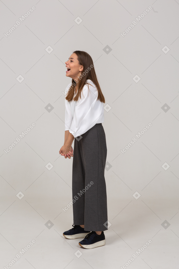Вид в три четверти смеющейся молодой леди в офисной одежде, держащейся за руки