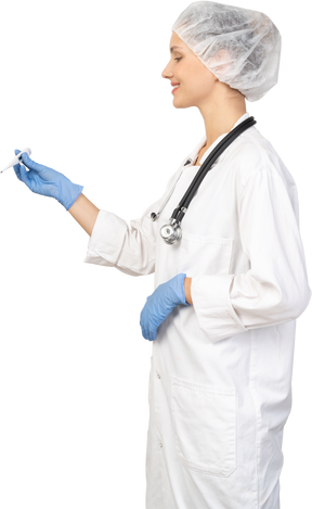 Side view of a young female doctor with stethoscope holding thermometer