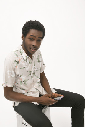 Afroman sitting on the baggage and using his smartphone