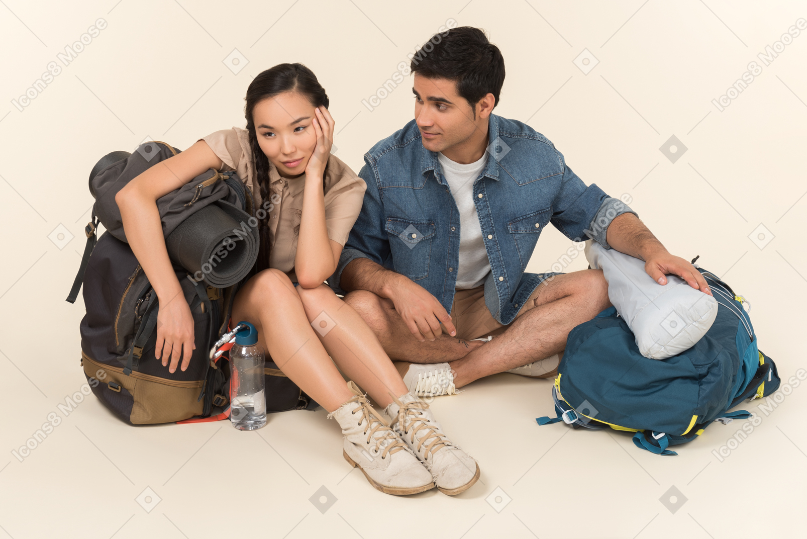 年轻的异族夫妇坐在巨大的背包附近