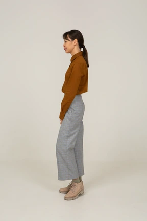 Side view of a pouting young asian female in breeches and blouse standing still