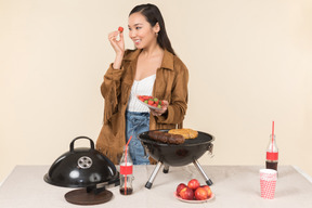 Joven mujer asiática haciendo una barbacoa y sosteniendo un plato de fresas