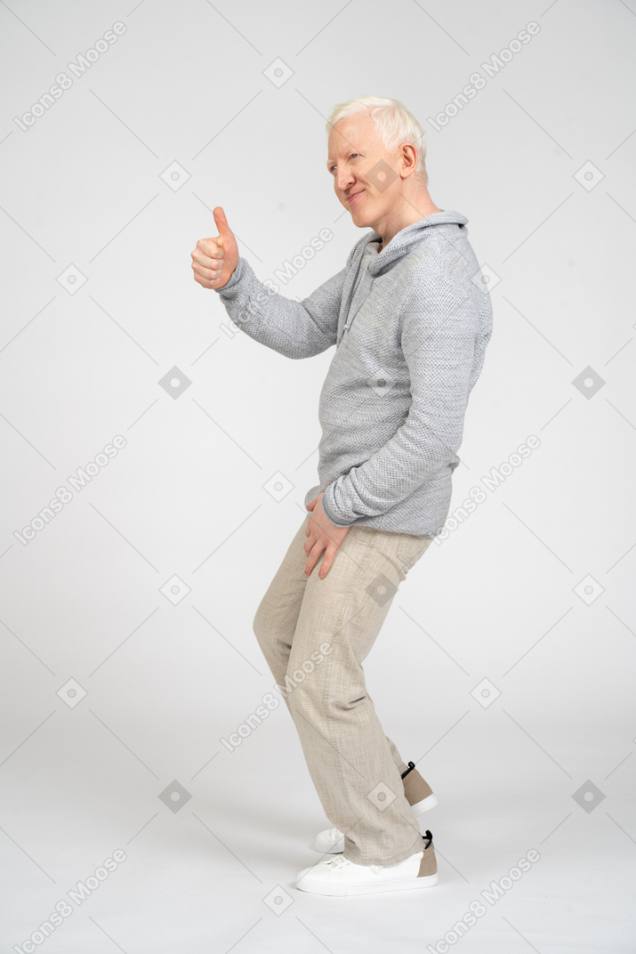 Side view of man crouching and giving thumbs up