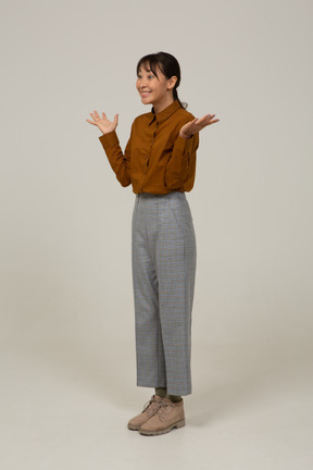 Three-quarter view of a delighted young asian female in breeches and blouse raising hands