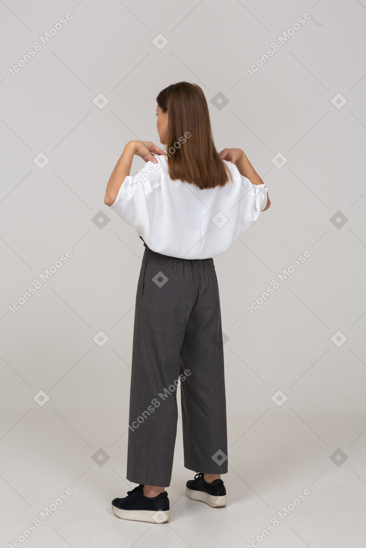 Vista traseira de três quartos de uma jovem com roupas de escritório tocando seus ombros