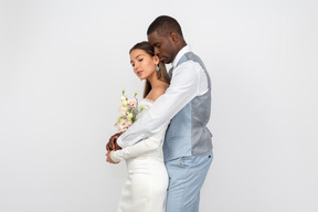 Bride and groom standing embraced with their eyes closed