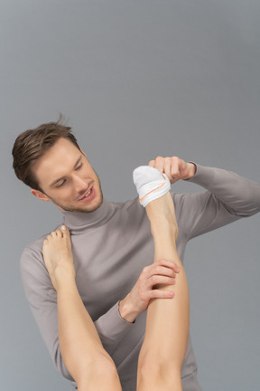 A cheerful young man wearing a sock on female`s foot