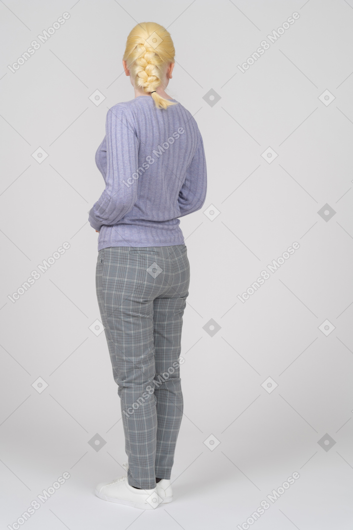 Женщина в повседневной одежде стоит спиной к камере