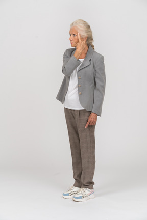 Vista lateral de una anciana en traje tocando la frente