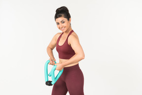 Young indian woman in sportswear holding hand expander