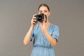 Front view of a young woman in blue dress taking shot