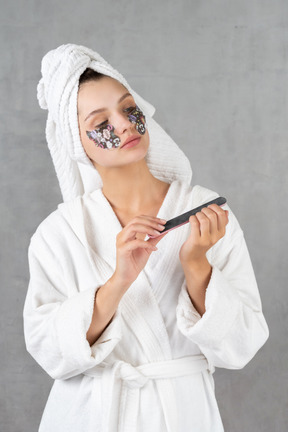 Woman in bathrobe filing her nails