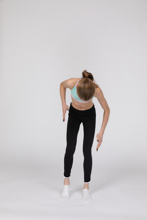 Front view of a teen girl in sportswear bending over and raising her hands