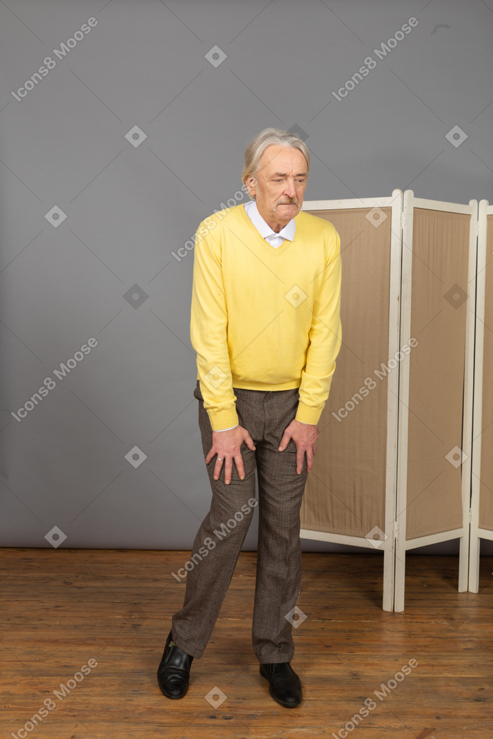Front view of a thoughtful old man putting hands on legs