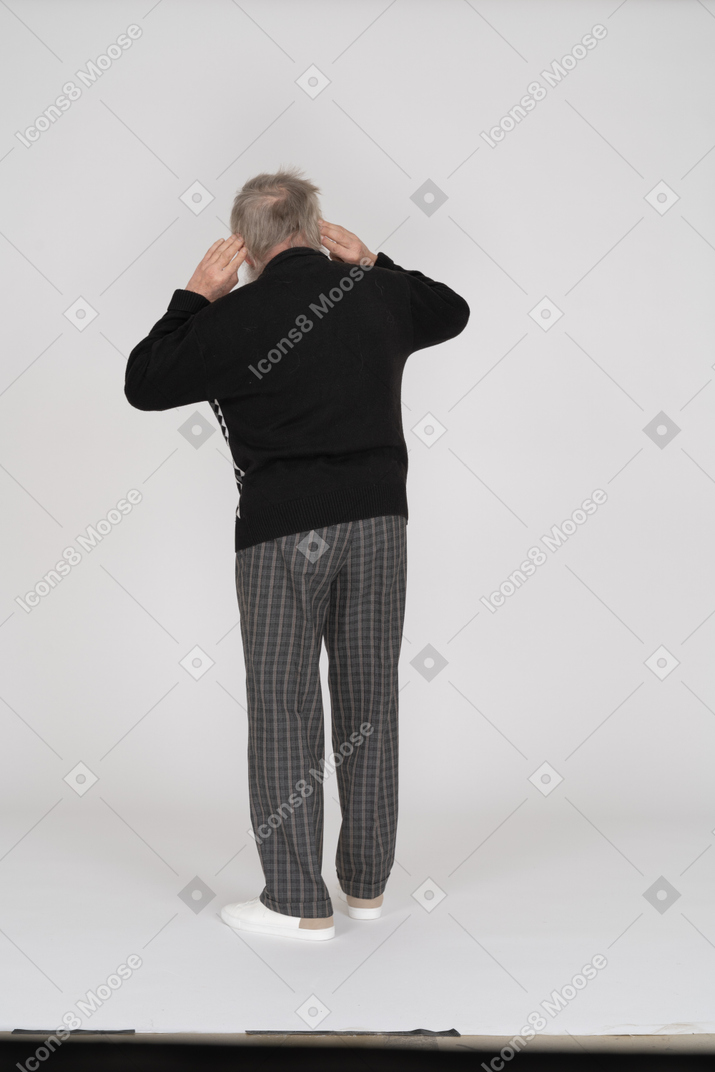 Rear view of old man with hands behind ears