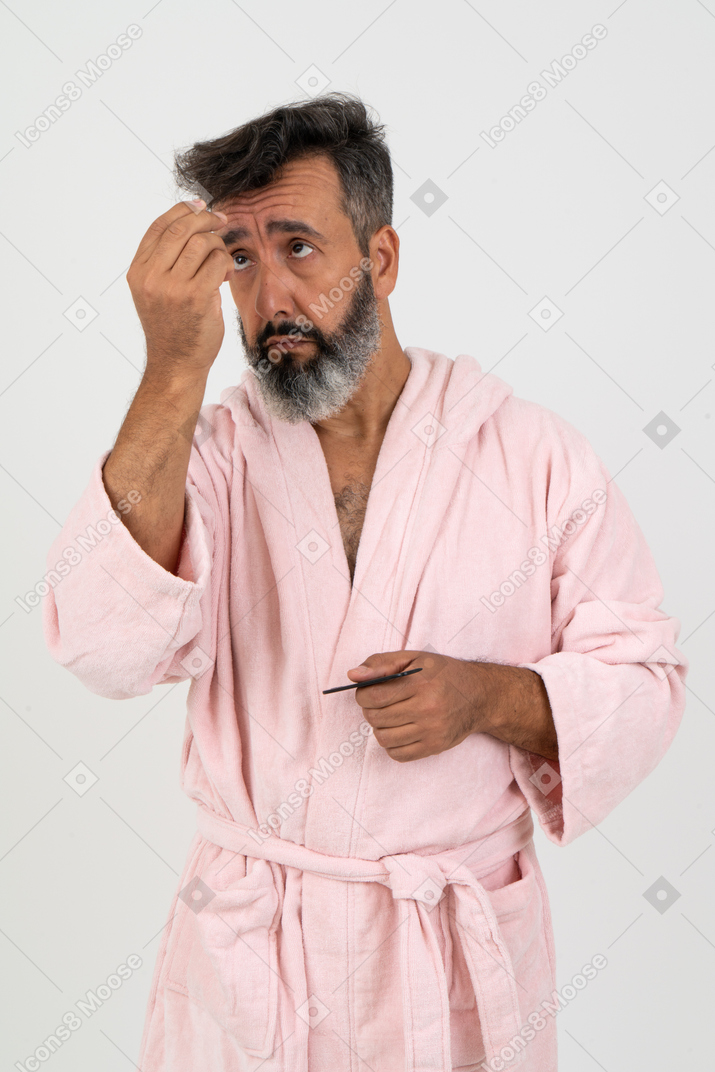 Зрелый мужчина смотрит на потерянные седые волосы