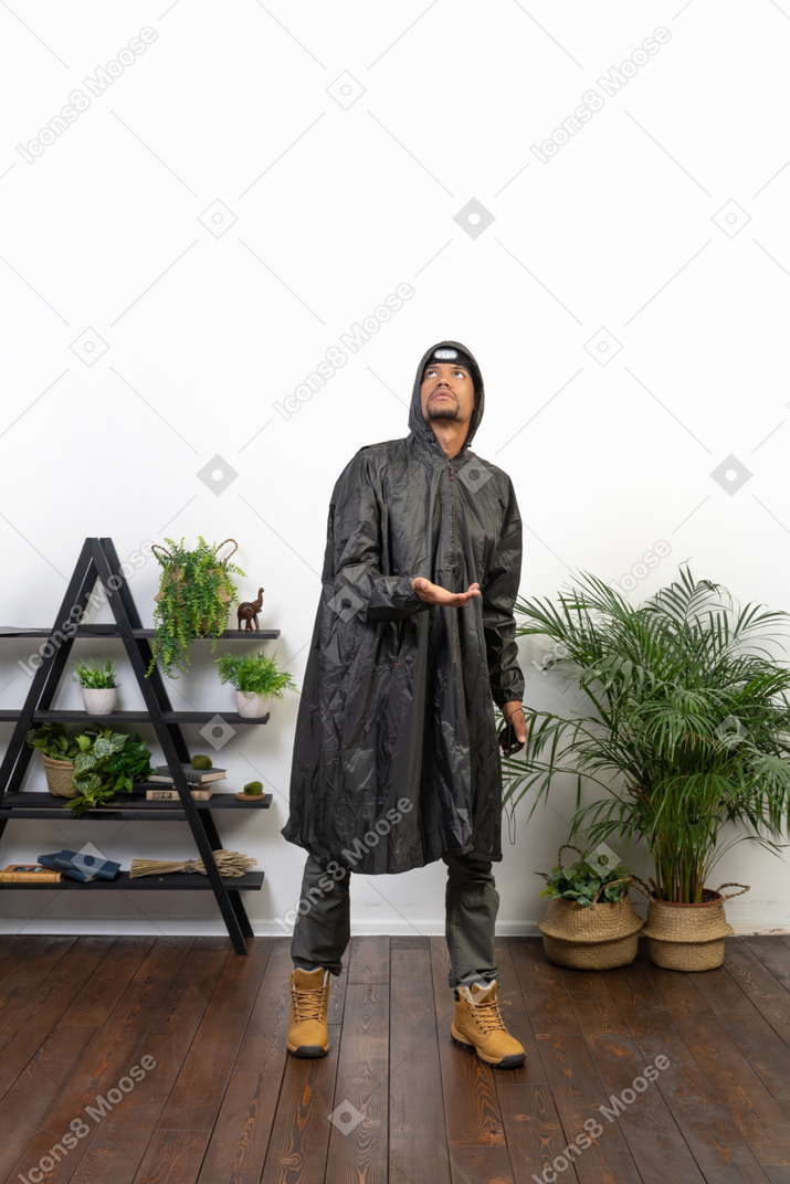 Мужчина в плаще ловит капли дождя на ладонь
