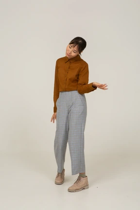 Side view of a young asian female in breeches and blouse tilting head and outstretching hand