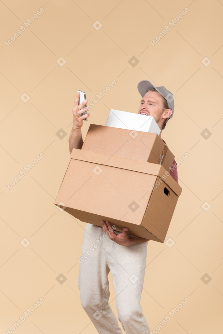 Delivery guy holding boxes and looking at phone