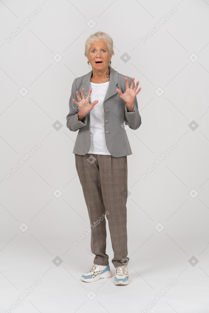 Front view of a scared old lady in suit looking at camera and gesturing