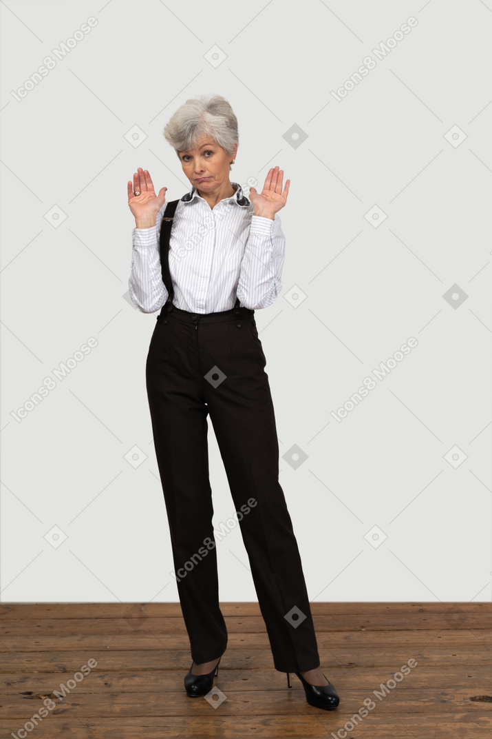 一位老无辜的女性在办公室服装打手势的前视图
