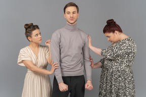 Young man showing his anger to two frightened women