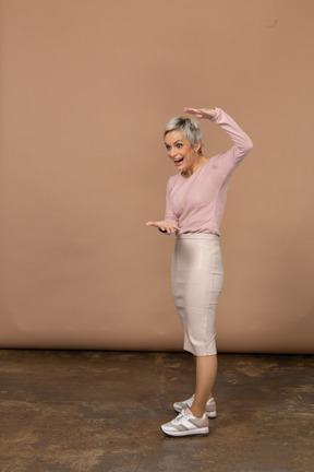 Vista lateral de una mujer en ropa casual que muestra el tamaño de algo