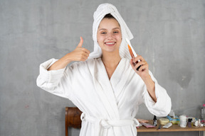 Mulher sorridente em roupão de banho mostrando os polegares