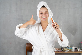 Smiling woman in bathrobe showing thumbs up