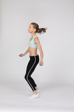 Side view of a teen girl in sportswear squatting and putting hands on hips