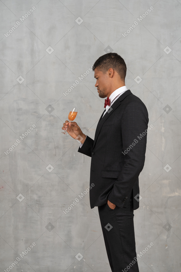 Man in formal wear looking at a glass of champagne