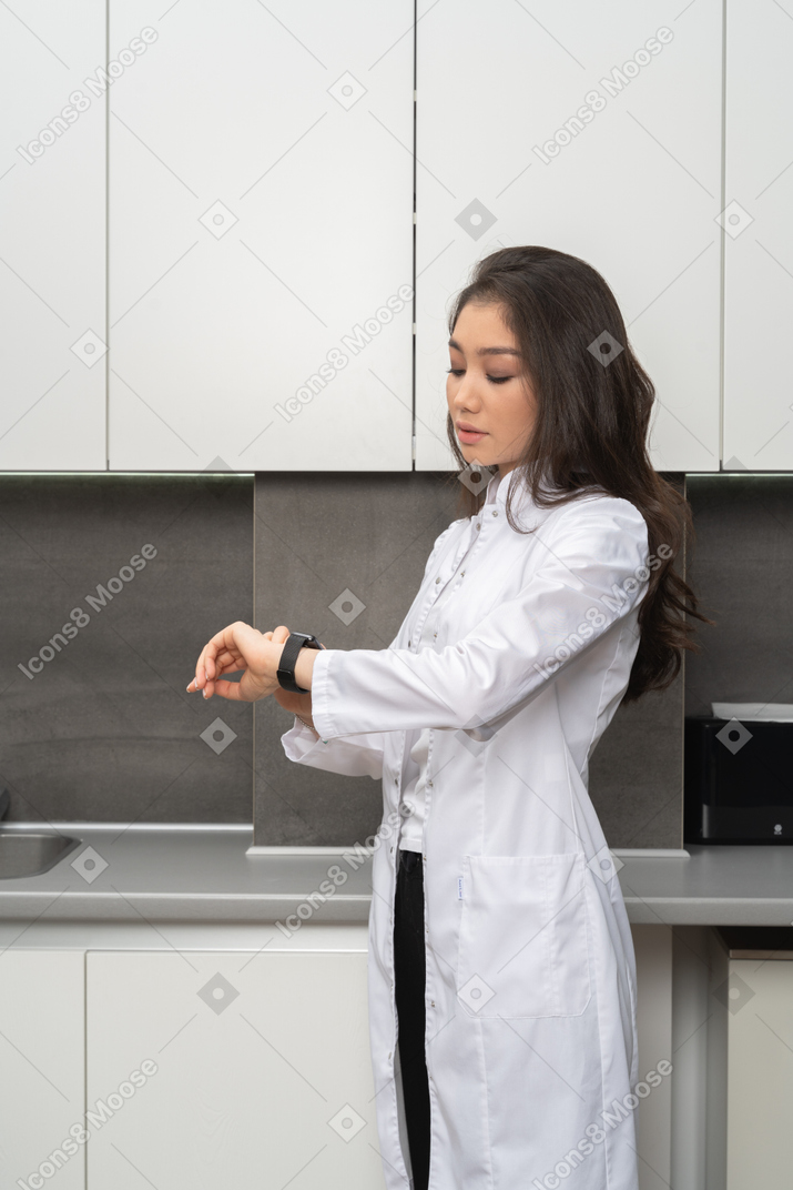 Three-quarters shot of a female nurse checking the time
