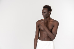 A young black man with a white bath towel around his waist doing his morning routine