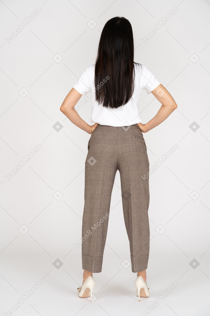 Back view of a young woman in breeches putting hands on hips