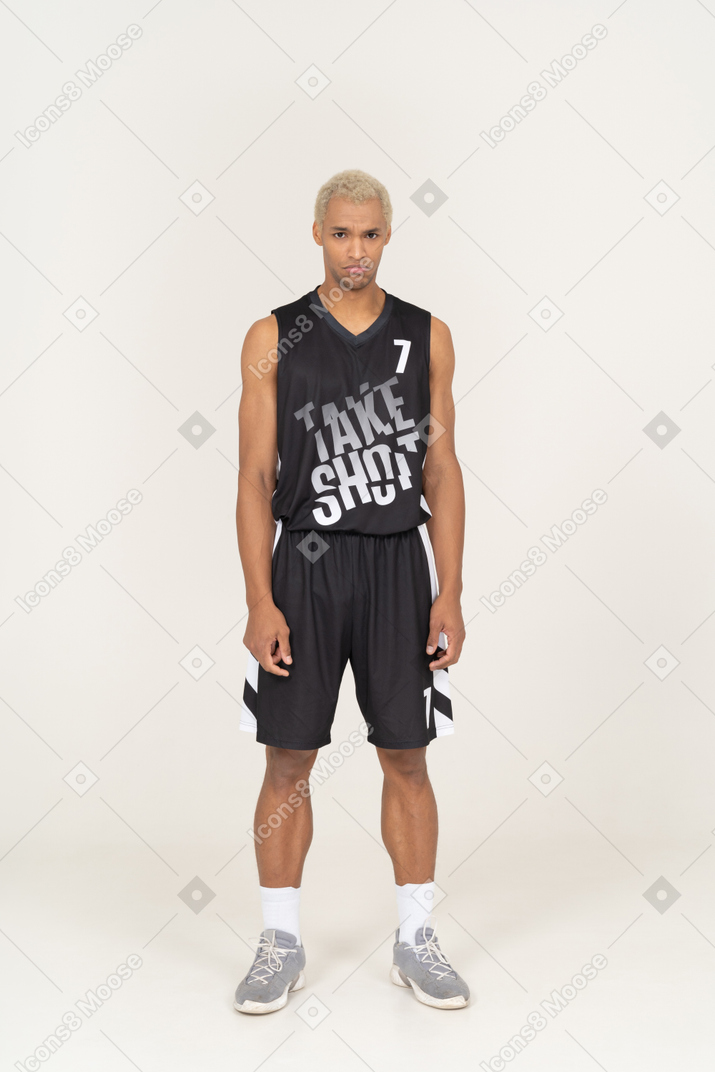 Vista frontale di un giovane giocatore di basket maschio triste in piedi ancora