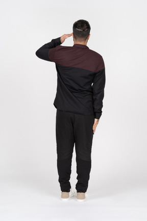 Back view of a man in casual clothes saluting