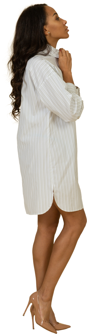 Vista lateral de uma jovem mulher de pele escura em um vestido branco ajustando o colarinho