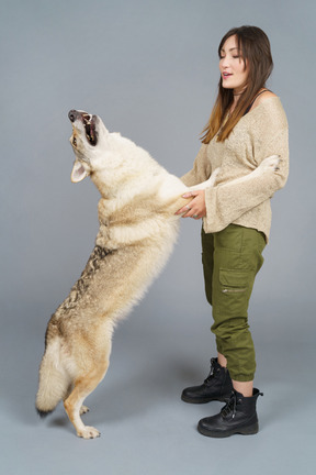 A figura intera di una giovane femmina che tiene le zampe del suo cane e guarda in basso