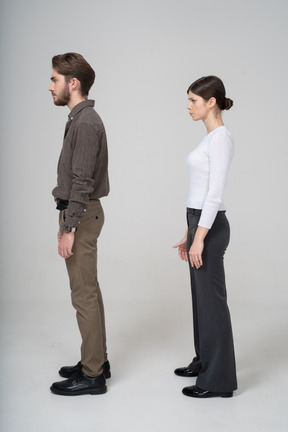 Side view of a moody young couple in office clothing standing still