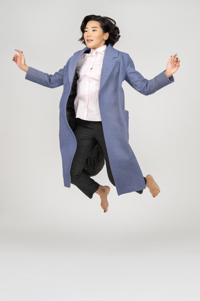 Молодая женщина в пальто прыгает