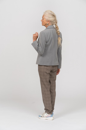 Vista posteriore di una vecchia donna in abito che mostra il pugno
